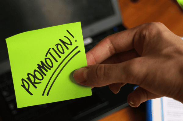 Woman Holding Promotions Sticky Note